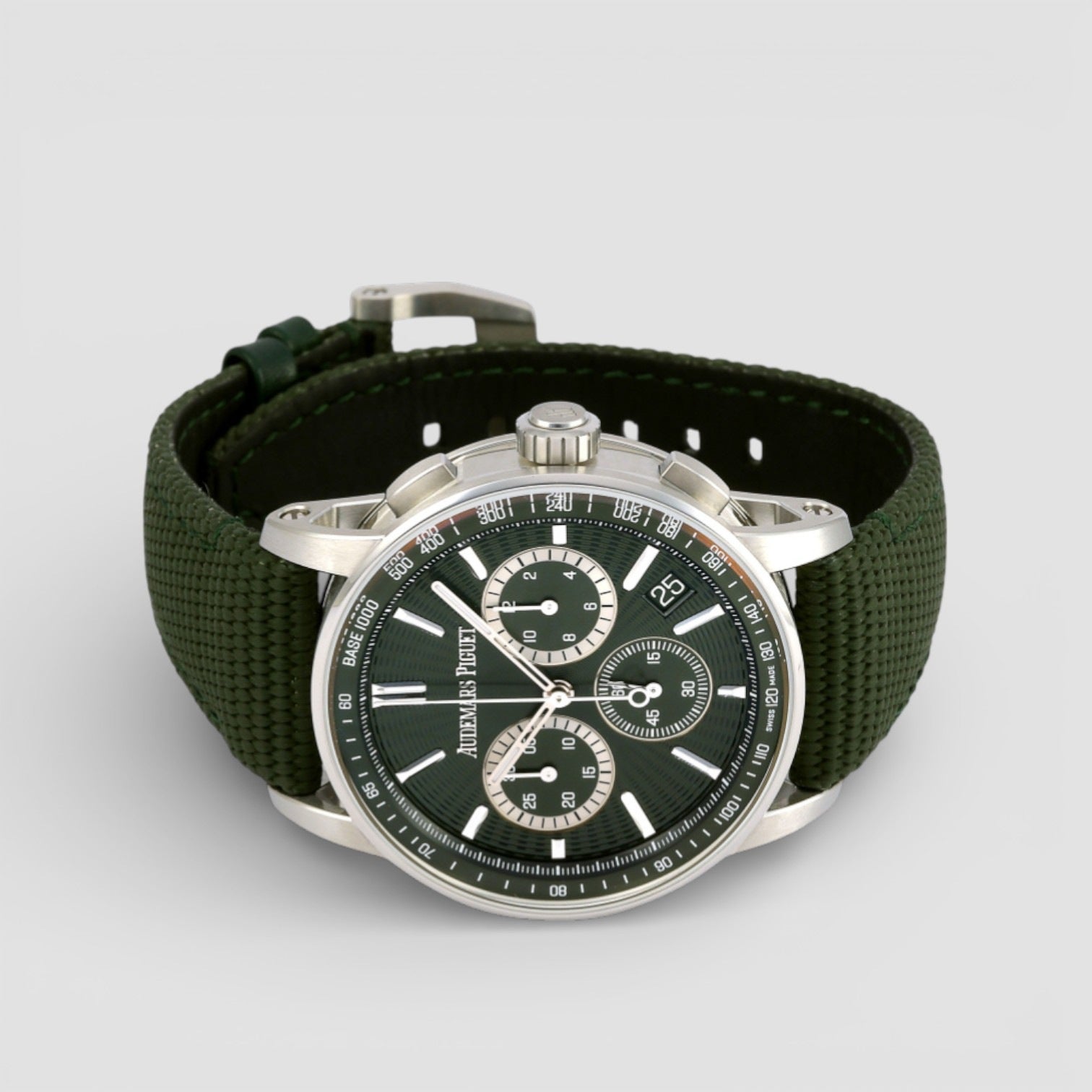 Wristwatch with green strap and black dial on a light gray background