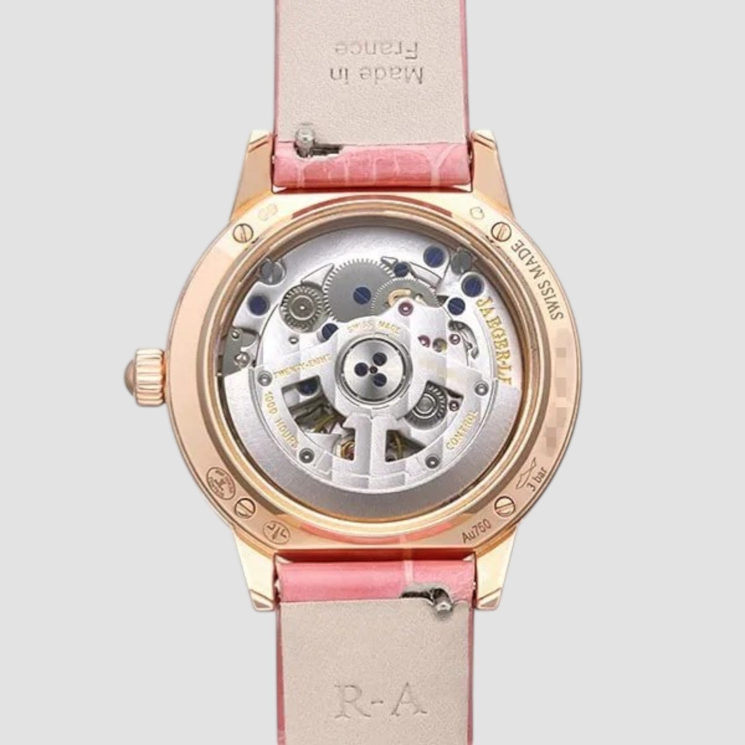 Watch with pink strap and visible mechanical components on a light gray background