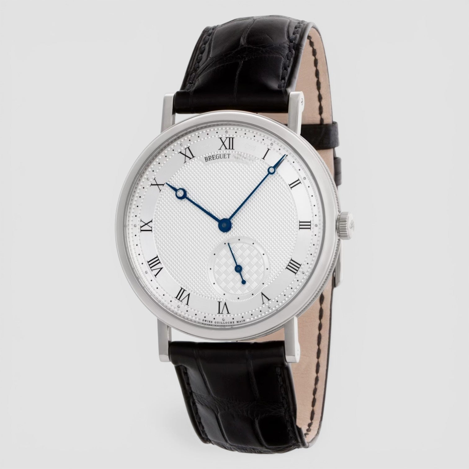 Wristwatch with black leather strap and white dial on a light gray background