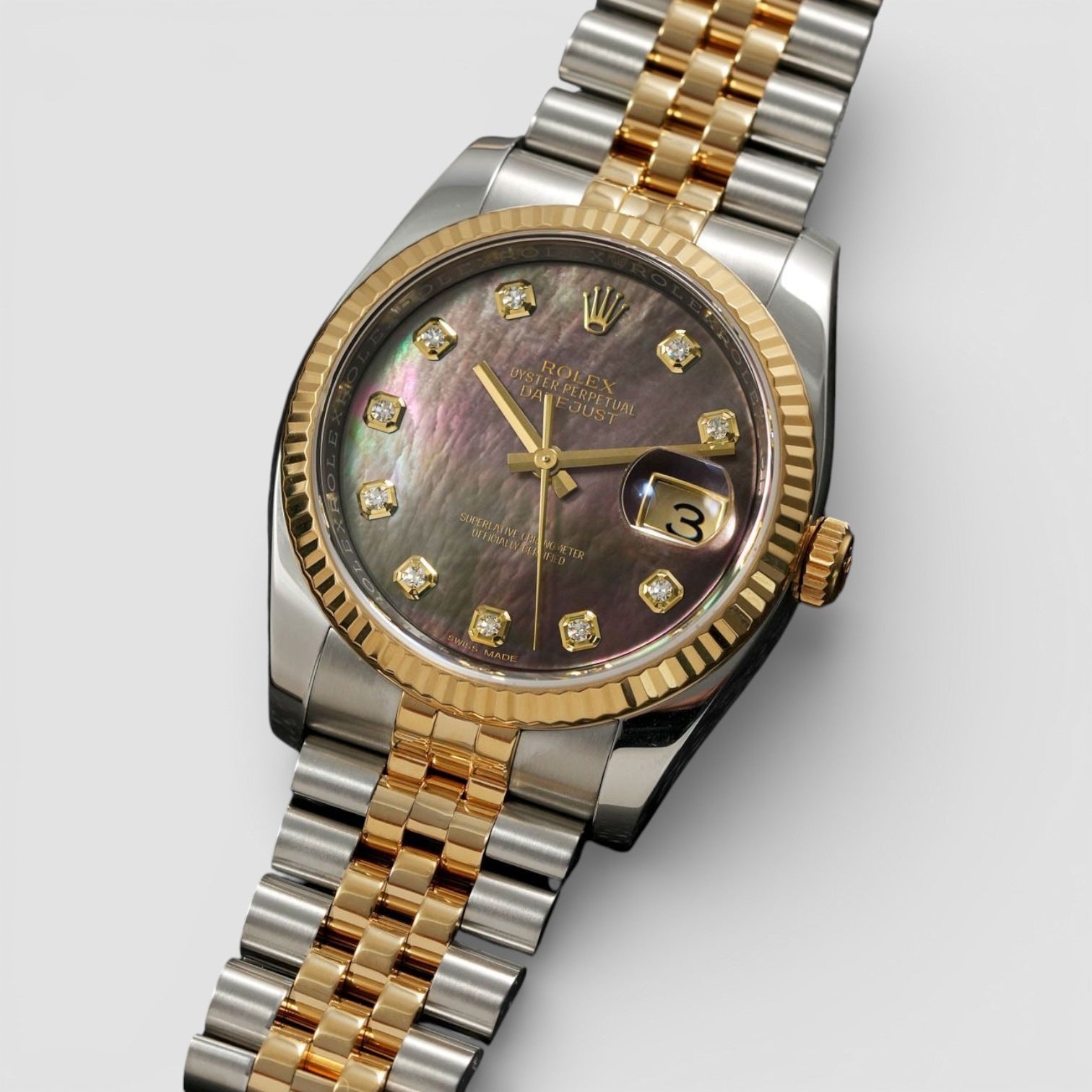 Luxury watch with two-tone gold and silver bracelet on a light gray background
